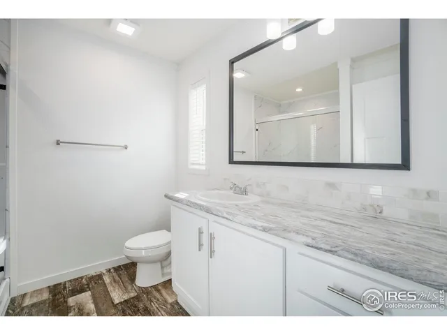 a bathroom with a granite countertop sink a toilet and a mirror