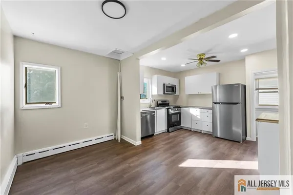 a kitchen with stainless steel appliances granite countertop a refrigerator sink and white cabinets