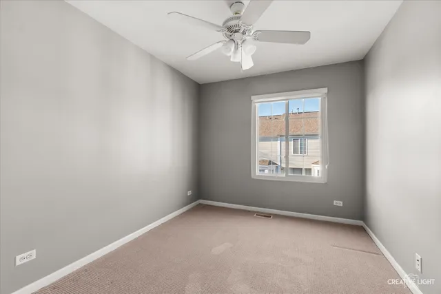 an empty room with a window and a fan