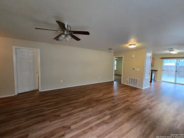 a view of a room with wooden floor and a ceiling fan