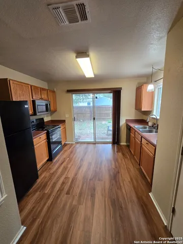 a open kitchen with stainless steel appliances a refrigerator stove and wooden floor
