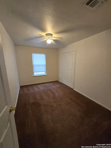 an empty room with windows and fan