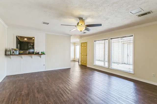 a view of an empty room with a window and wooden floor