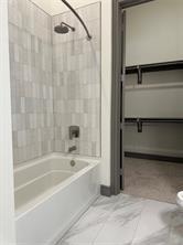 2700 Old Denton Road, Unit 1043 Carrollton, TX 75007 - Photo 4 of 14 Full bathroom featuring bathing tub / shower combination, a spacious closet, and light marble finish floors