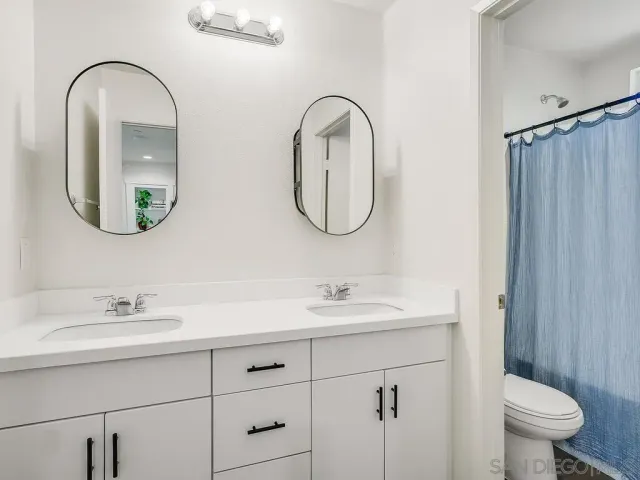 a bathroom with 2 sink toilet and a mirror