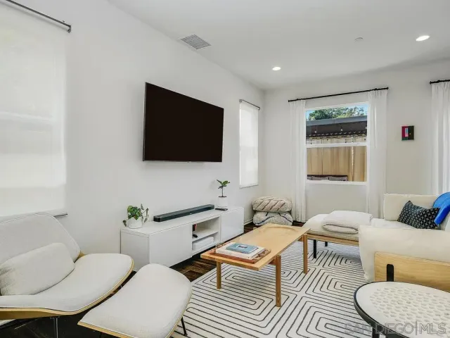 a living room with furniture a flat screen tv and a window