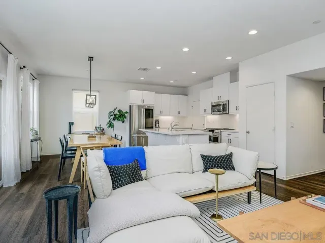 a living room with kitchen island furniture and a dining table with wooden floor
