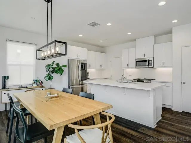 a kitchen with kitchen island a stove a table and chairs in it
