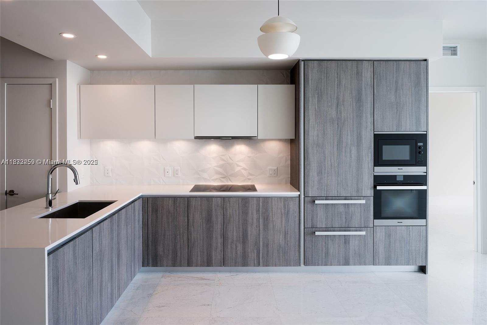 2900 Northeast 7th Avenue, Unit 1603 Miami, FL 33137 - Photo 4 of 6 a kitchen with kitchen island granite countertop a sink stove and refrigerator