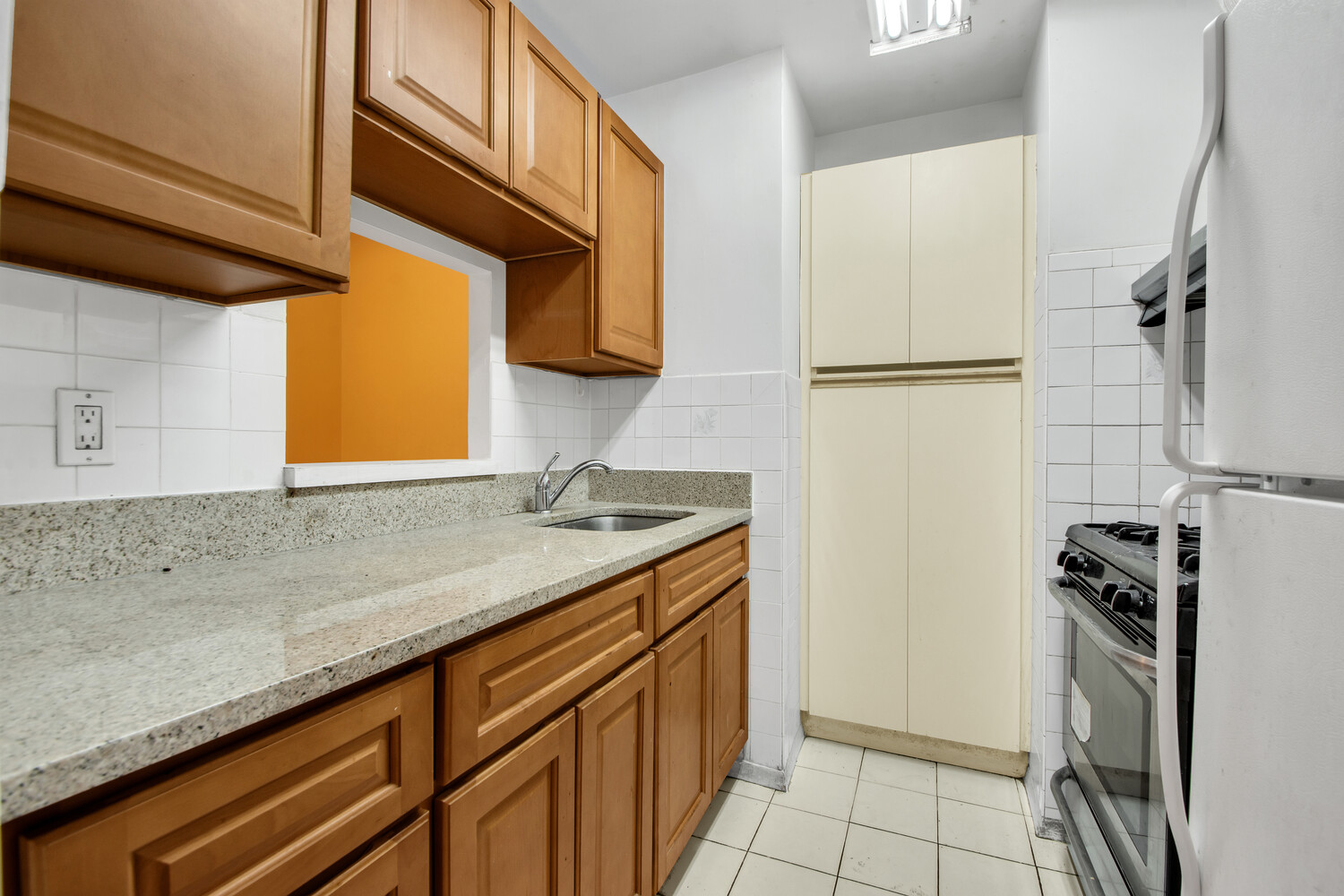 414 West 54th Street, Unit 5C Manhattan, NY 10019 - Photo 4 of 8 a kitchen with a sink a refrigerator and cabinets