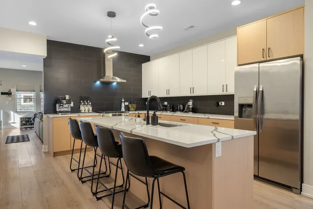 a kitchen with stainless steel appliances kitchen island granite countertop a sink a stove a refrigerator and island with wooden floor