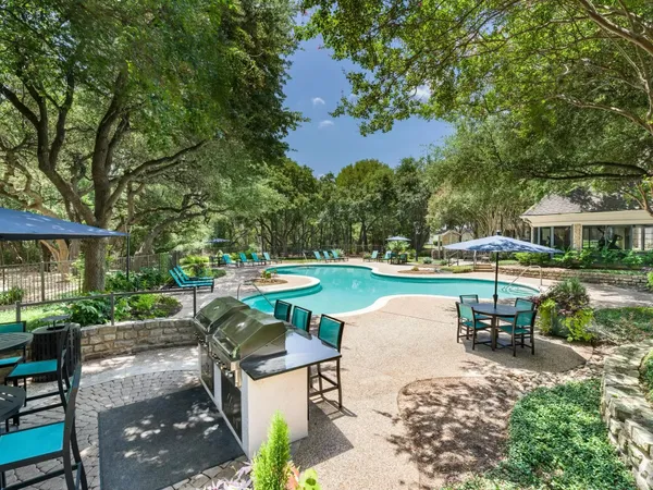 a view of a patio with table and chairs under an umbrella with large trees