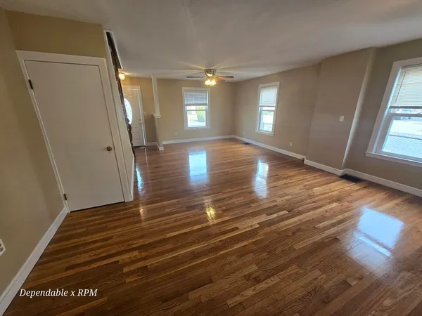 an empty room with wooden floor and windows