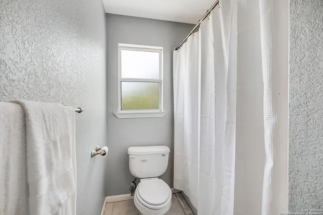 a bathroom with a toilet and a shower curtain