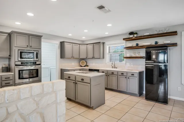 a kitchen with stainless steel appliances granite countertop a stove top oven a sink and a refrigerator