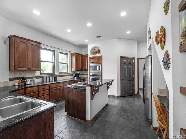 a kitchen with stainless steel appliances granite countertop sink stove and refrigerator