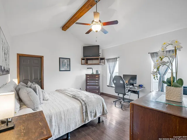 a bedroom with a bed a chair and potted plant on the dresser