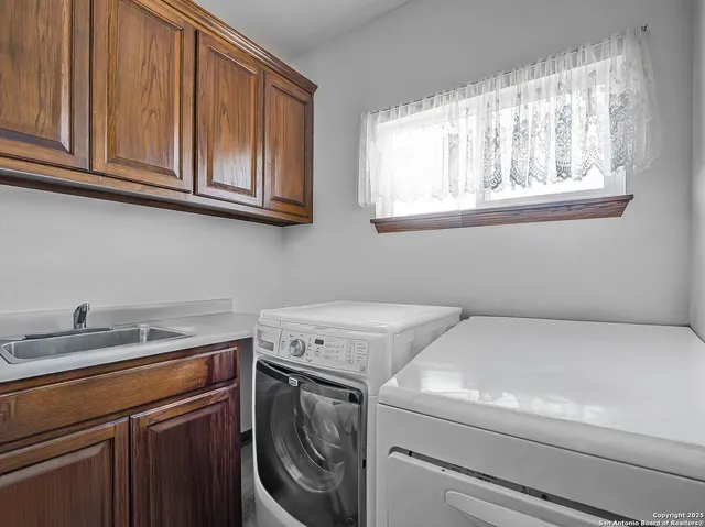 a utility room with stainless steel appliances white cabinets and a washer dryer