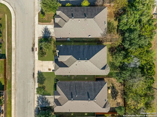 an aerial view of a house with swimming pool and large trees