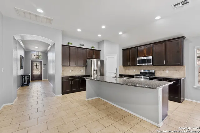 a large kitchen with granite countertop a stove top oven a sink a counter space and cabinets