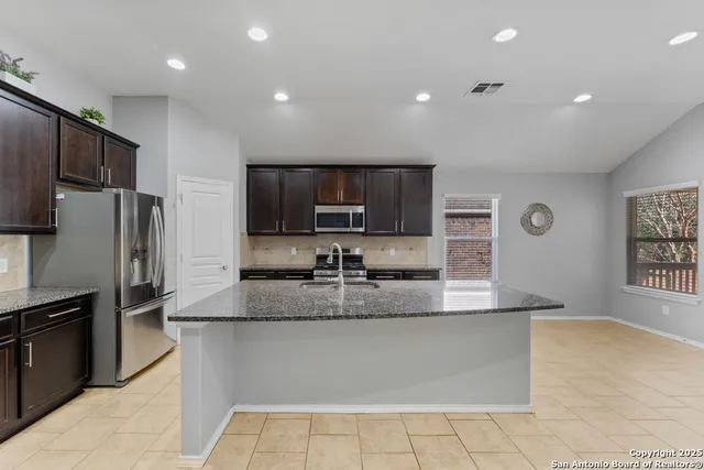 a kitchen with stainless steel appliances granite countertop a sink a stove a refrigerator a microwave and island
