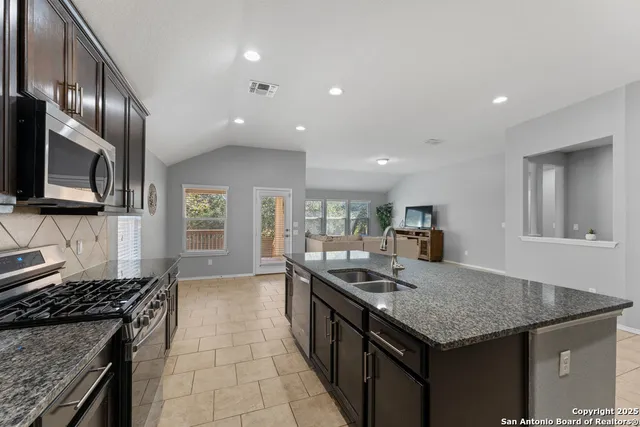 a kitchen with granite countertop stainless steel appliances a sink stove and cabinets