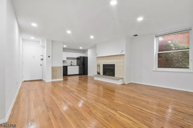 a view of empty room with wooden floor and fireplace