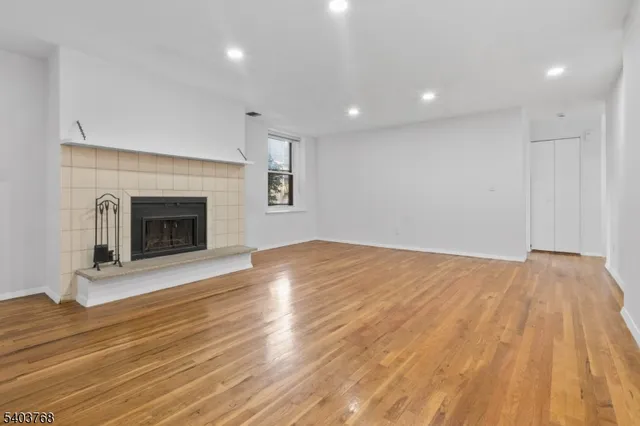 a view of empty room with wooden floor and fireplace
