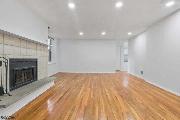 a view of empty room with wooden floor and fireplace