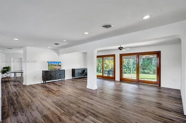 a view of a living room a kitchen with wooden floor and a window