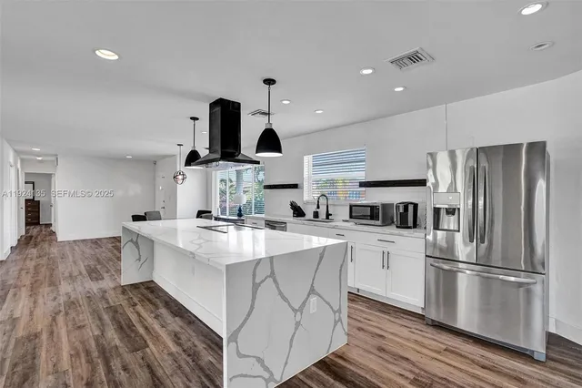 a kitchen with kitchen island a white counter top space cabinets and stainless steel appliances