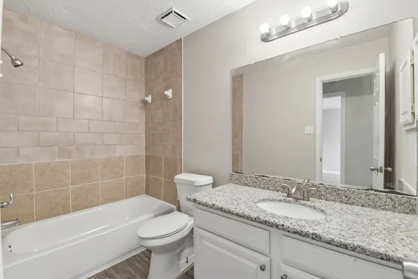 a bathroom with a granite countertop toilet a sink and bathtub