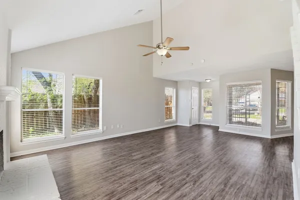 a view of an empty room with wooden floor and a window