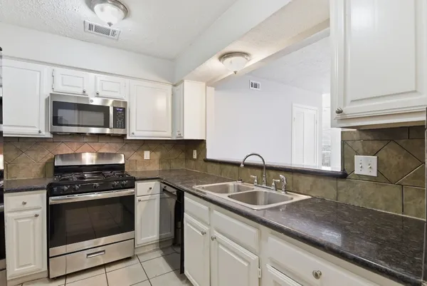 a kitchen with granite countertop a sink stove and microwave