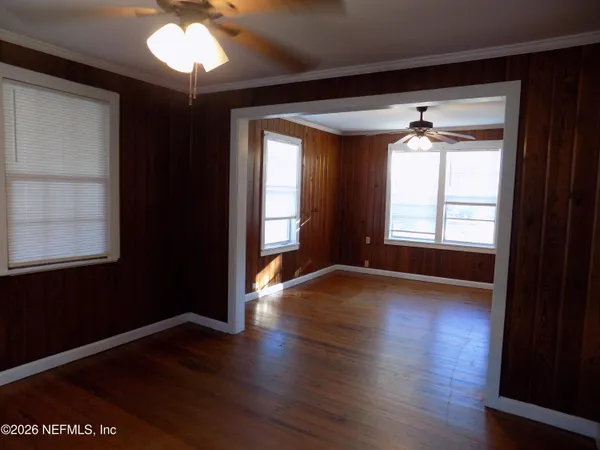 an empty room with wooden floor and windows