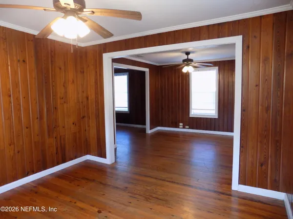 an empty room with wooden floor fan and windows