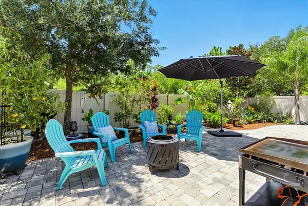 a view of a table and chairs under an umbrella in backyard