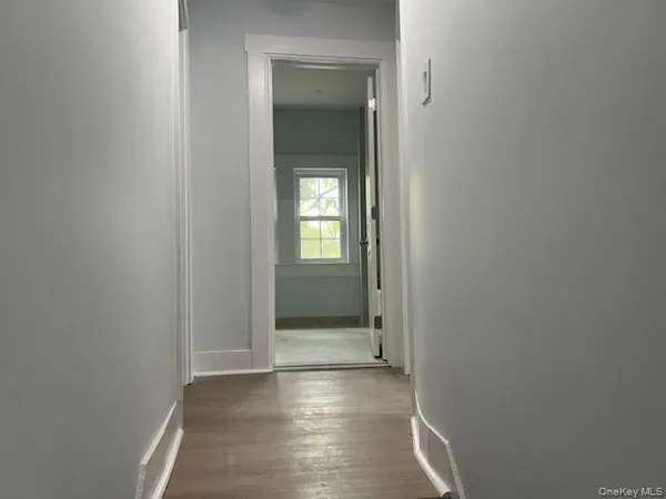 a view of a hallway with wooden floor and a bathroom