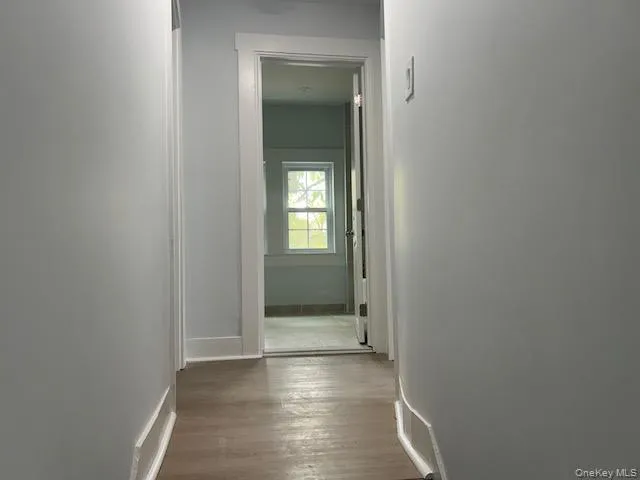 a view of a hallway with wooden floor and a bathroom