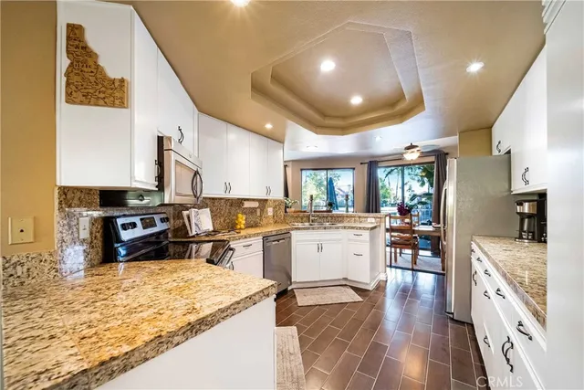 a kitchen with stainless steel appliances granite countertop sink stove refrigerator and wooden floor