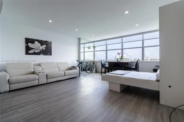 a living room with furniture a large window and wooden floor