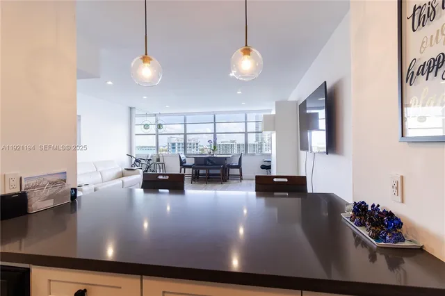 a view of a room with kitchen island stainless steel appliances wooden floor dining table and chairs