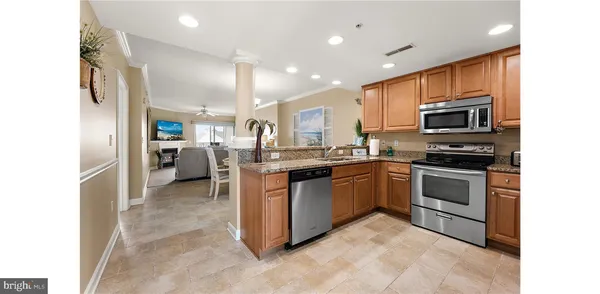a kitchen with stainless steel appliances kitchen island granite countertop a stove top oven a sink and a refrigerator
