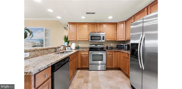 a kitchen with stainless steel appliances granite countertop a refrigerator a stove and a sink