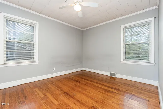 a view of empty room with wooden floor and fan