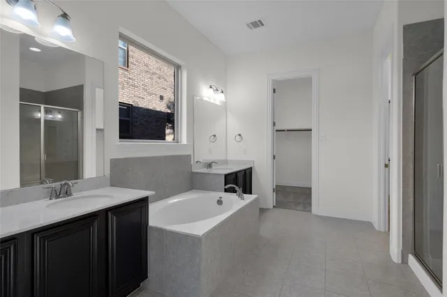 a bathroom with a sink double vanity granite tub shower and a mirror