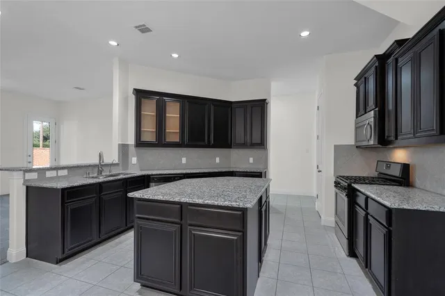 a kitchen with stainless steel appliances granite countertop wooden cabinets a stove top oven and a sink