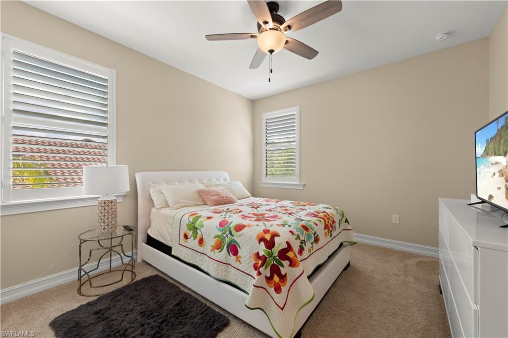 1608 Mockingbird Drive Naples, FL 34120 - Photo 23 of 29 a bedroom with a bed a chandelier and a window