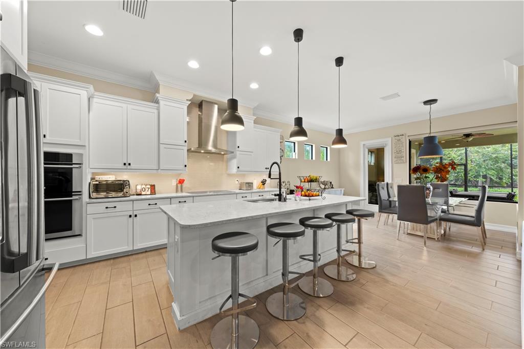 1608 Mockingbird Drive Naples, FL 34120 - Photo 8 of 29 a kitchen with stainless steel appliances granite countertop a sink a stove a refrigerator and island with wooden floor