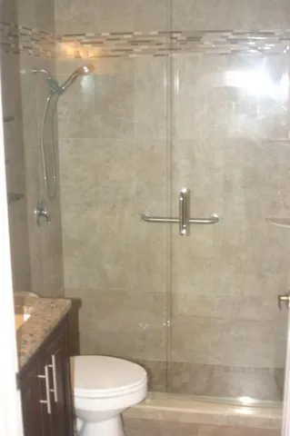 a bathroom with a granite countertop shower a toilet and a sink